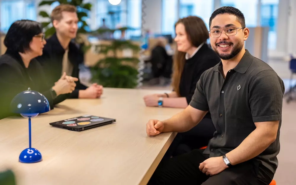 Medarbetare som ler mot kameran, kollegor runt om på Axfoods kontor