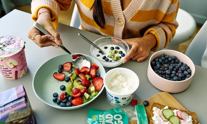 Nyttigt mellanmål med frukt, bär, keso, gröt och torkad mango